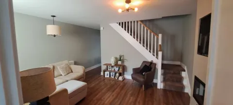 Open-plan living room painted in soft sage green with white stairs
