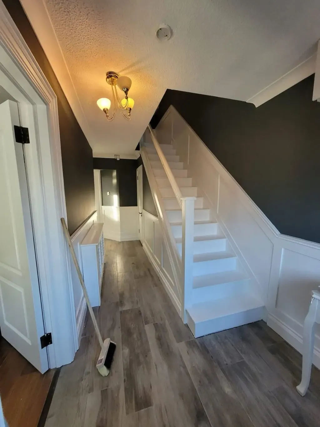 Hallway and staircase with charcoal walls, white wainscoting and freshly painted white stairs