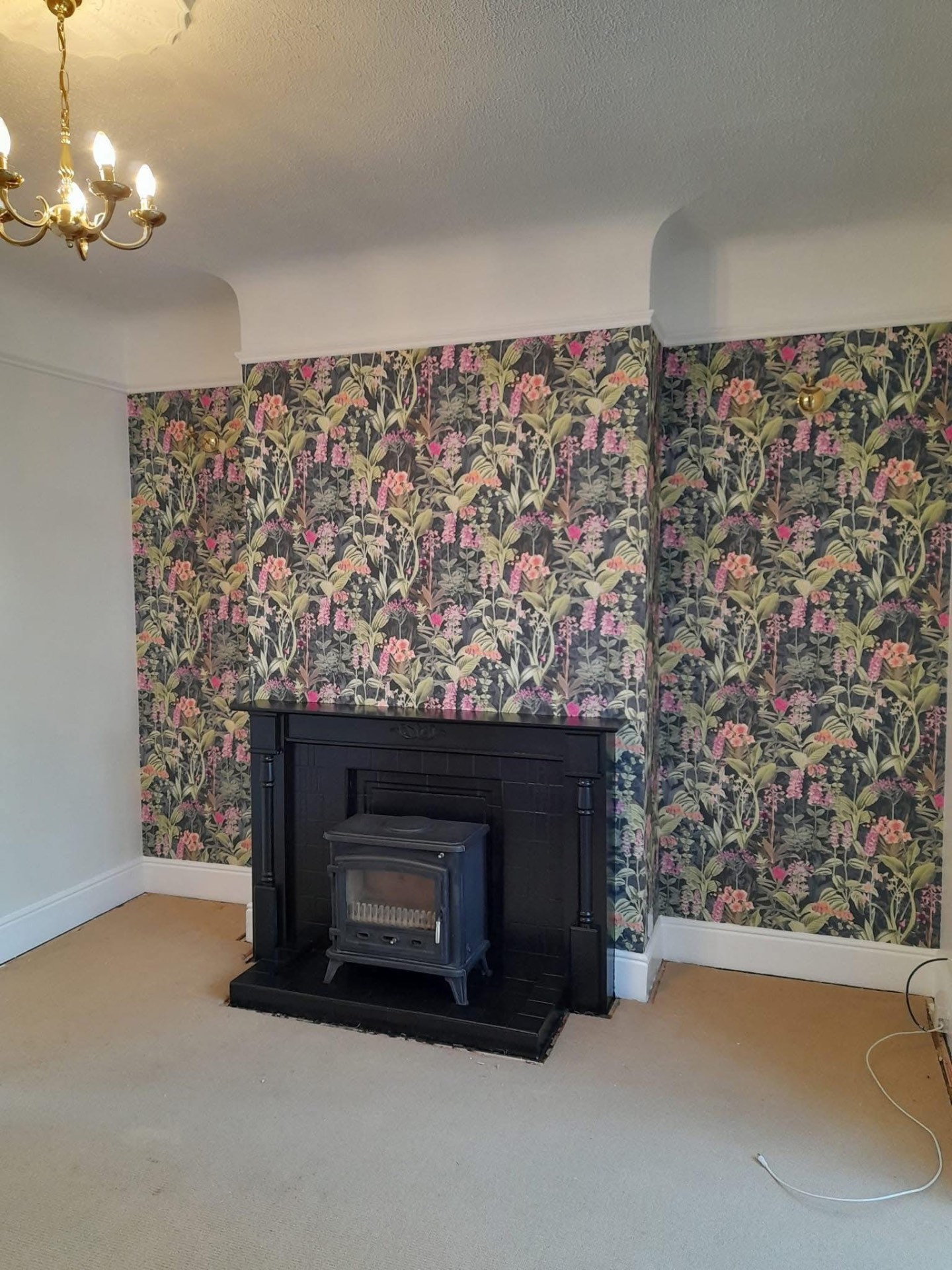 Chimney breast hung with botanical floral wallpaper in pink and green