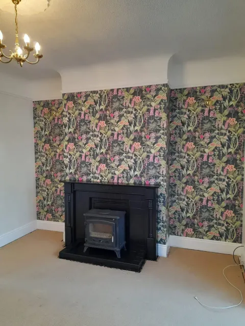 Chimney breast hung with botanical floral wallpaper in pink and green