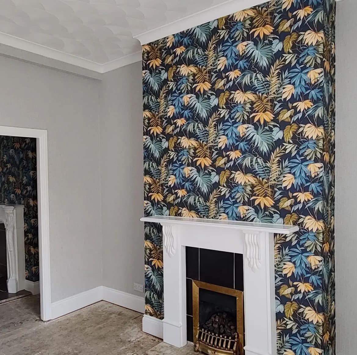 Feature wall with navy tropical leaf wallpaper around white fireplace