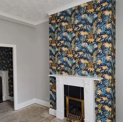 Feature wall with navy tropical leaf wallpaper around white fireplace
